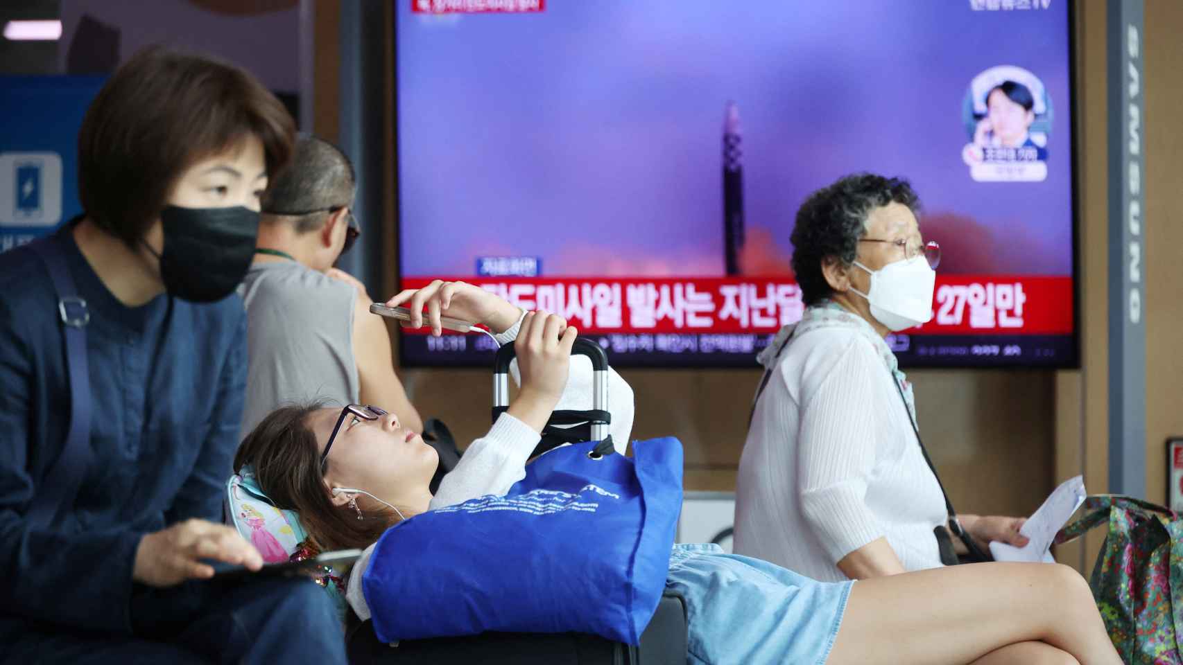 Passageiros esperam pelo comboio em frente a um televisor que transmite uma notícia sobre o disparo de um míssil balístico pela Coreia do Norte ao largo da sua costa leste, numa estação de comboios em Seul, Coreia do Sul.