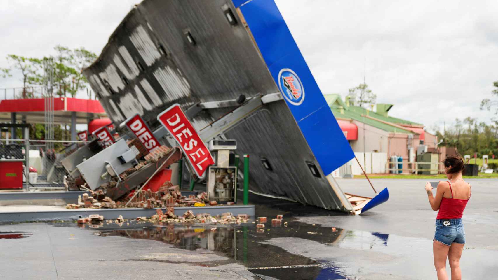 Uma mulher olha para uma estação de serviço destruída depois de o Idalia ter atingido a Florida.